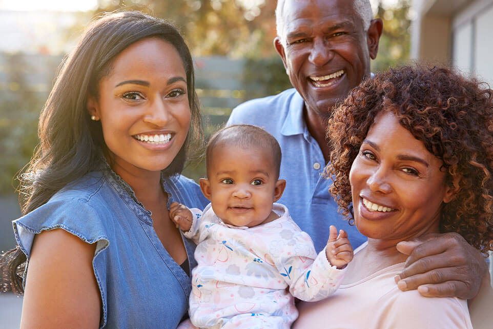 Portrait Of Grandparents With Adult Daughter And Baby Granddaughter In Garden At Home Together