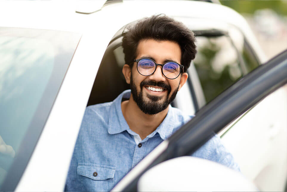 Cheerful young man driver sitting inside white car